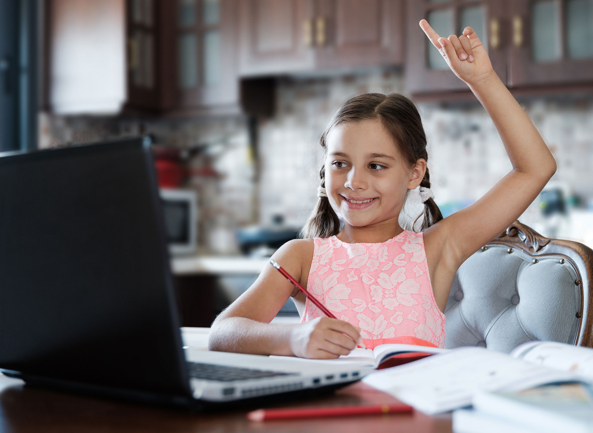 Girl raising her hand to ask a question while working at the computer